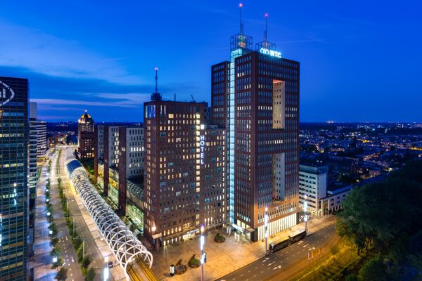 Avondelijke stadszicht op de Prinses Beatrixlaan in Den Haag met het WTC-gebouw en modern verlichte infrastructuur.